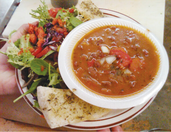 A Photo showing homemade chili, salad, and bread with sauce